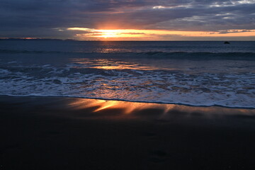 The beach at dawn when the sun's rays dye the waves red. Japanese natural background material.