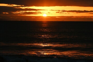 Fototapeta premium The beach at dawn when the sun's rays dye the waves red. Japanese natural background material.