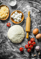 Raw pizza. Dough with cheese and cherry tomatoes.
