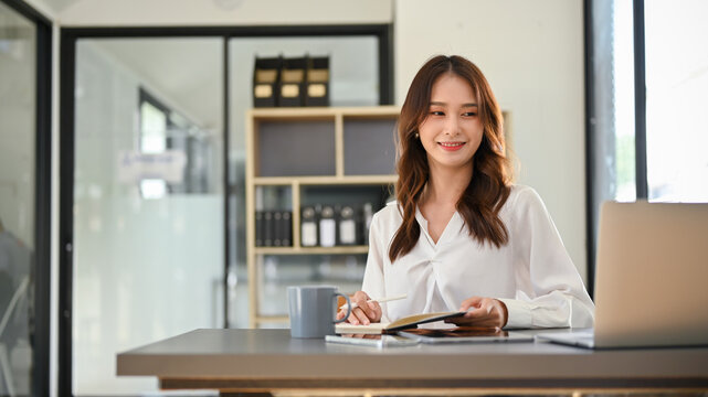 Beautiful And Happy Millennial Asian Businesswoman Working At Her Desk In Her Private Office