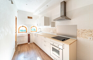 Renovated kitchen area with two arched windows and white walls