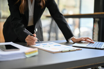 Professional Asian business leaning on table, reviewing financial document. cropped image