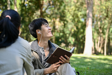Happy young Asian male college student enjoys spending time in the park with his friends
