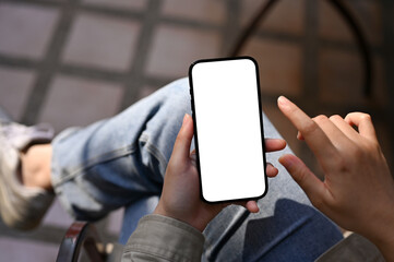 Top view, A female using her smartphone while sitting at the cafe, phone white screen mockup