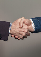 Business people in suit shaking hands, get an agreement, against grey wall background