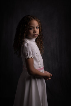 Classic painterly renaissance studio portrait of young mixed race girl in white dress