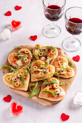 Heart shape mini pizzas on wooden board for Valentines day holiday, top view