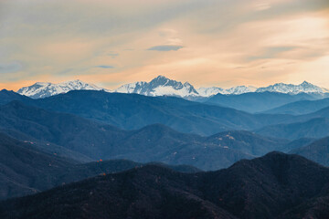 Stunning view of the ridge of mountain peaks from a height. Mountain peaks of the Caucasus on a sunny day. A magnificent mountain range with high snow-capped peaks. View from a height of 1000 m.