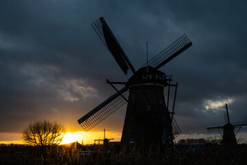 Plakat sunset silhouette of iconic windmills in Kinderdijk Netherlands. Landmark functional buildings originally made to pump flood water out of low land polder to preserve farm land reclaimed from the sea