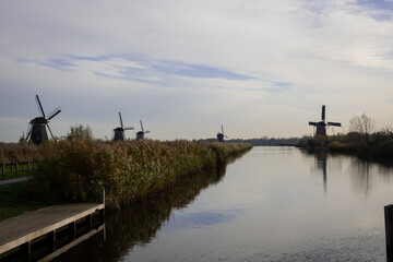 Fototapeta na wymiar iconic windmills in Kinderdijk Netherlands next to canal waterway flood management. Landmark buildings originally made to pump water out of low land polder to preserve land reclaimed from the sea