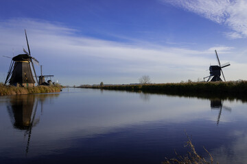 iconic windmills in Kinderdijk Netherlands next to canal waterway flood management. Landmark buildings originally made to pump water out of low land polder to preserve land reclaimed from the sea
