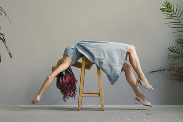 Lying down on chair lady posing scenic photography. Picture of woman in linen dress with wall, houseplants on background. High quality wallpaper. Photo concept for ads, travel blog, magazine, article