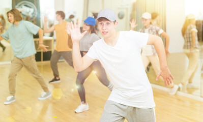 Group of active teens rehearsing modern dance in studio.