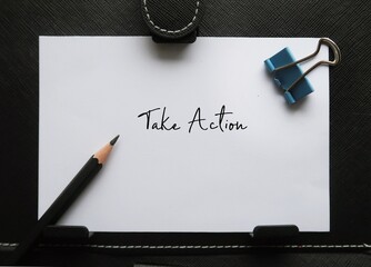 Paper note on black background with handwritten text TAKE ACTION, concept of start the process of...