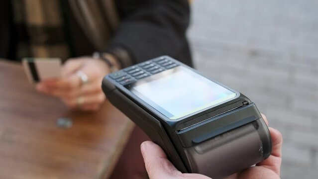 Detail of a man's hand paying with a credit card at a payment terminal