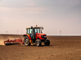 Obraz premium Springtime seeding preparations, tractor at work on the fertile fields