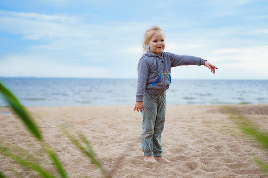 little girl having fun on sandy beach pointing somewhere. Image with selective focus