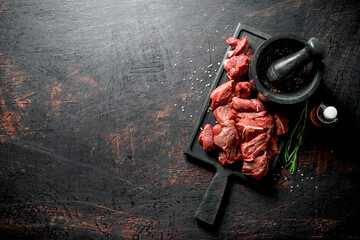 Sliced raw beef, rosemary,oil and pestle mortar.