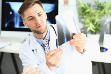 Naklejka na ściany i meble Male doctor examines x-ray of leg and arm in clinic