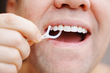 a man's mouth close-up. a man brush your teeth plastic toothpick with dental floss. concept of hygiene and health of teeth and oral cavity. daily care and brushing of teeth.