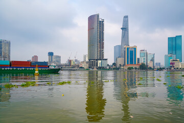 Obraz premium Hochiminh, Vietnam JAN 14 2023: Early morning in District 2 looking over District 1, seeing bitexco tower, IFC One building, cargo ships moving on the Saigon River