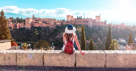Woman sitting on wall,  enjoying beautiful panoramic view of Alhambra Granada view- Andalusia in...