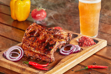 Ribs de porc avec ses légumes en accompagnement sur plancha et verre de bière sur un fond de bois avec de la fumée   