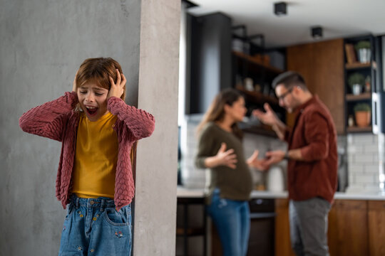 Stressed child covering her ears suffering due to domestic violence, going through an agony, having an unhappy childhood because of the egoistic parents.