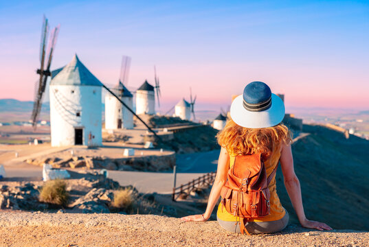 Woman tourist looking at windmills with castle, Consuegra, Castile-La Mancha, Spain