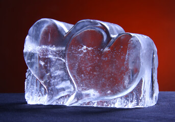 Two hearts made from a rock salt crystal. Statuette with hearts on a red background. Two transparent hearts.