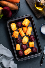 Hasselbeck-style chopped root vegetables on a black tray.