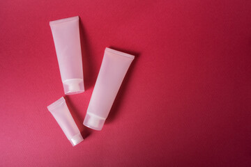 Mockup three plastic tubes of different sizes for cream on a background of magenta color