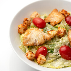 A plate of lettuce on a white background. Salad with chicken fillet, parmesan cherry, croutons and lettuce. 