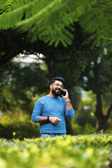 Young indian man talking on smartphone at park.