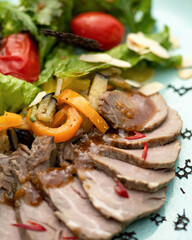 Sliced baked meat with vegetables. Close-up. Blue background. 