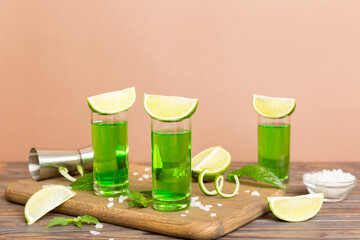 Sweet refreshing mint liqueur, with ice and mint leaves on table background, Shots with lime slice and mint flat lay