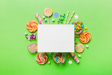 Flat lay holiday composition. Paper blank, lollipop, birthday decorations on Colored background. Top view, copy space for text