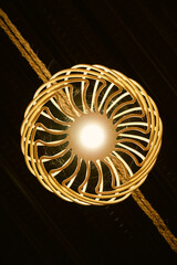 Bottom view of yellow bulb with rattan woven ornament that hanging in the rope. Inspiration for modern lighting and home decoration. Rattan chandelier for vintage and abstract background. Wicker Lamp.