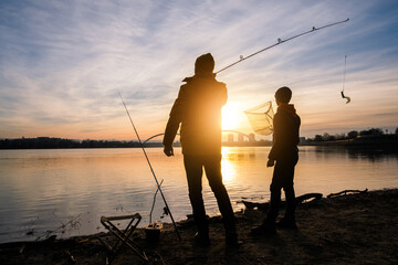 Father and son are fishing on winter day. River fishing.