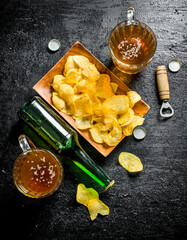 Beer in mugs and a bottle of chips on a plate.