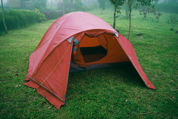 Red tent on the garden grass with foggy background