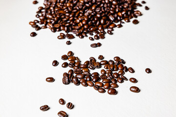Roasted coffee beans on white leather sheet.