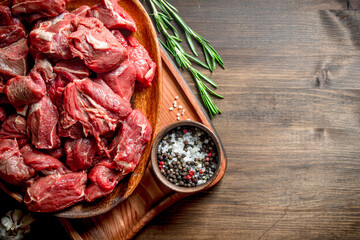 Sliced raw beef on a plate with rosemary and seasonings in a bowl.