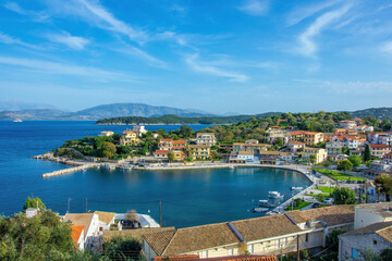 Obraz premium view of beautiful Kassiopi village – sea lagoon with calm turquoise water, cruise boats, colorful houses and street café