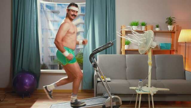 funny seductive athlete with a mustache runs on a treadmill and looks into the camera