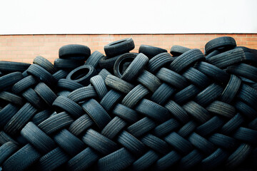 Pile of used rubber tires on the brick wall background with white copy space. Recycle and reusable ideas. Selective focus, copy space.