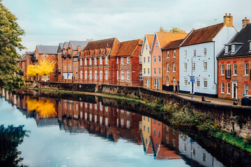 Street view with colorful brick houses near river in the small english town Norwich, England in...