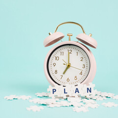 Alarm clock with the word plan standing on puzzle pieces, brainstorming for new ideas, planning new goals and resolutions