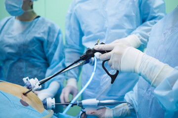 Laparoscopic surgical instruments in the hands of surgeons. Selective focus. Hands of surgeons in...