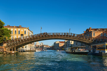 Accademia bridge with tourists embarking on the Baporeto and the church of Our Lady of Health to the background